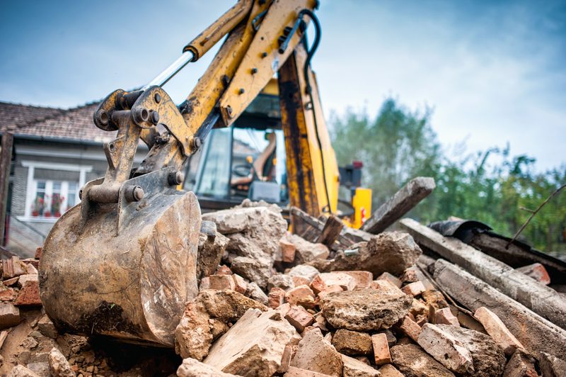 Excavator tearing down a residential structure on a Bakersfield demolition job